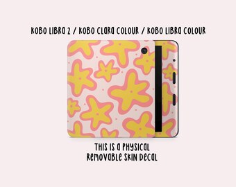 Könnte beinhalten: Ein abnehmbarer Skin-Aufkleber für Kobo Libra 2, Kobo Clara Colour und Kobo Libra Colour E-Reader. Der Aufkleber zeigt ein Muster aus gelben und rosa sternförmigen Designs auf hellrosa Hintergrund. Der Text "THIS IS A PHYSICAL REMOVABLE SKIN DECAL" ist ebenfalls sichtbar.