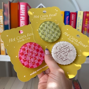 以下が含まれることがあります： ピンク、グリーン、ホワイトのフォントで「Hot Girls Read」と書かれた、チェック柄のイエローのカードストック製ブックマーク3つ。ブックマークは、Kindleグリップとして使用できるように設計されています。