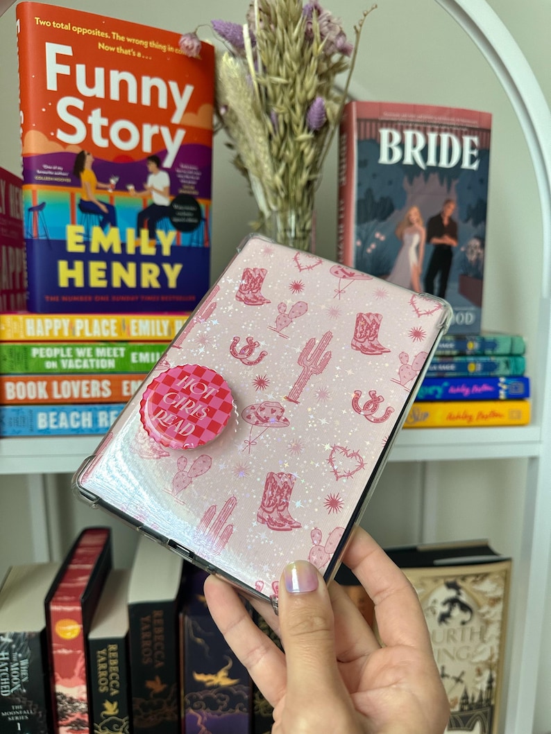 May include: A pink and white phone case with a glittery finish and a pink cowboy boot pattern. The case has a pink and white button that says "Hot Girls Read".