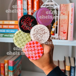 Peut inclure: Cinq aimants circulaires en forme de capsule de bouteille avec le texte Hot Girls Read. Les aimants comprennent un noir avec du texte rouge, un violet avec du texte doré, un blanc avec du texte marron, un à carreaux vert clair et un rose.