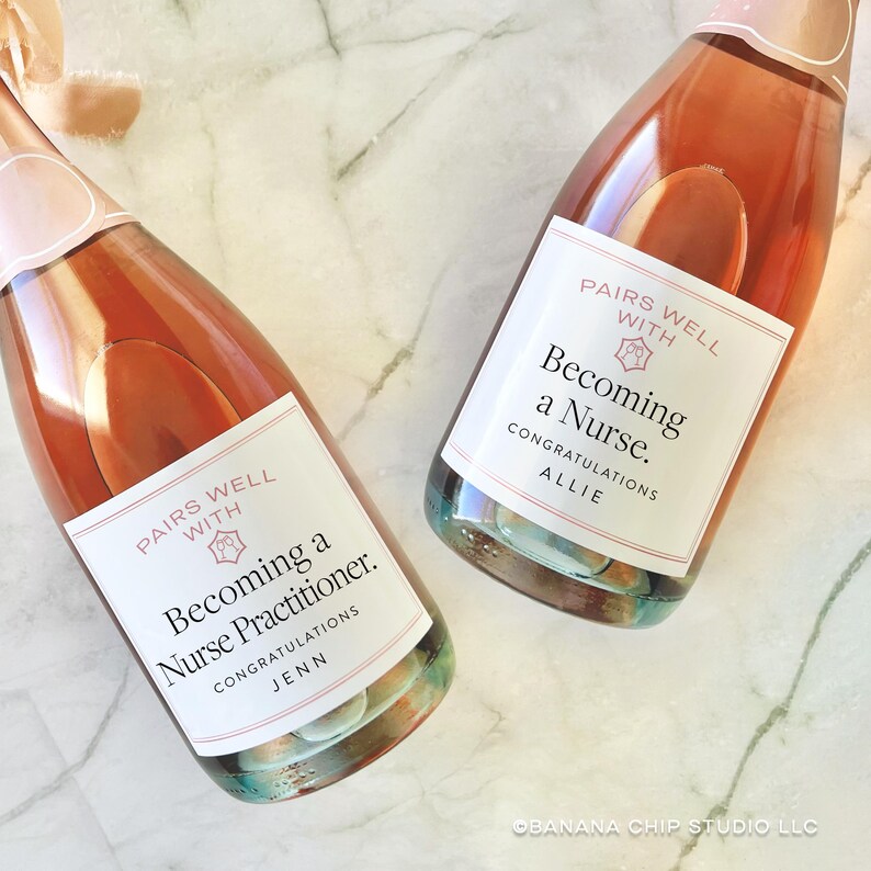 May include: Two bottles of sparkling wine with pink labels that read "Pairs Well With Becoming a Nurse Practitioner. Congratulations Jenn" and "Pairs Well With Becoming a Nurse. Congratulations Allie."