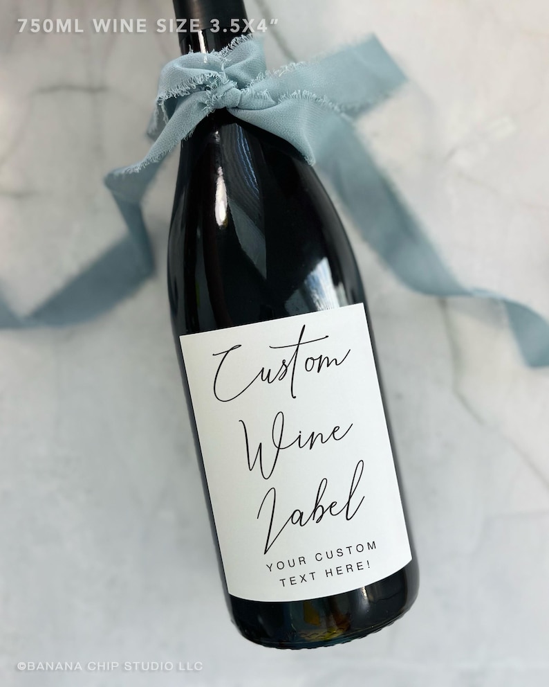 May include: A black wine bottle with a white label that reads "Custom Wine Label" and "Your Custom Text Here!". The bottle is tied with a light blue ribbon. The bottle is 3.5 x 4 inches and holds 750ml of wine.