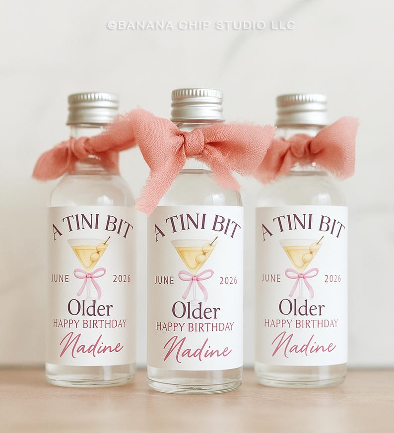 Puede incluir: Tres botellas de vidrio peque&ntilde;as con tapas plateadas y lazos rosas. Cada botella tiene una etiqueta que dice "A Tini Bit" con una ilustraci&oacute;n de martini, la palabra "Older", "Happy Birthday" y el nombre "Nadine". Las botellas son para un cumplea&ntilde;os.