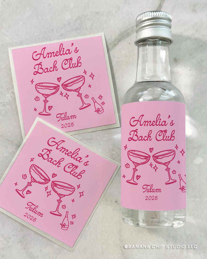 May include: A clear glass bottle with a silver cap and two square stickers, all featuring a pink label with the text Amelia's Bach Club, Tulum 2025, and illustrations of two clinking cocktail glasses, small hearts, stars, and a champagne bottle.