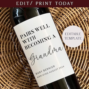 以下が含まれることがあります： 白いワインボトルのラベルに、黒い文字で「Pairs well with becoming a Grandma」と「Baby Bernier Arriving August 2024」と書かれています。ラベルは茶色の籐の背景に貼られています。