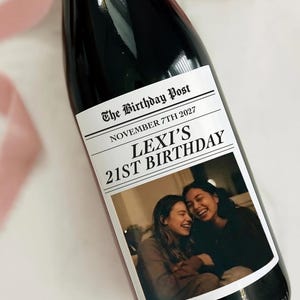May include: A dark wine bottle with a custom label. The label reads "The Birthday Post" and "Lexi's 21st Birthday" with a photo of two smiling people. The bottle is 3.5 x 4 inches and holds 750ml of wine.