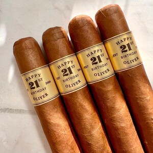 May include: Four brown cigars with gold labels that say "Happy 21st Birthday Oliver" and the year established.