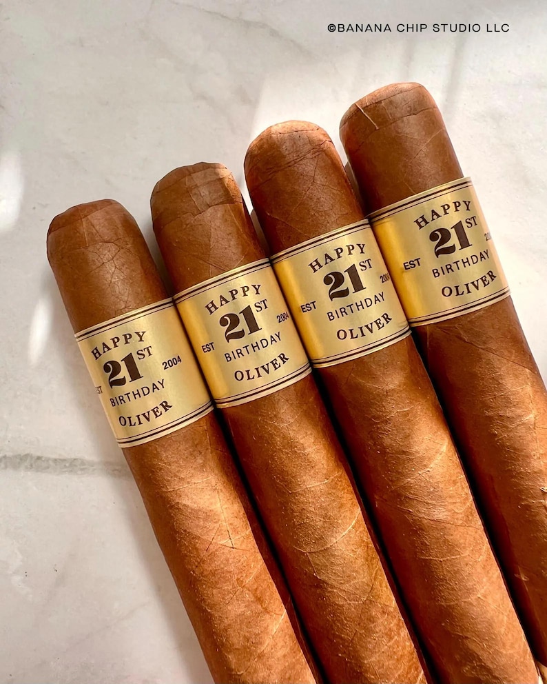 May include: Four brown cigars with gold labels that say "Happy 21st Birthday Oliver" and the year established.
