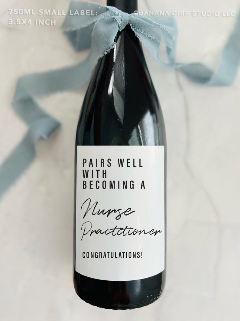 May include: A dark wine bottle with a white label that reads "Pairs Well With Becoming a Nurse Practitioner." The bottle is tied with a light blue ribbon. The label is 8.89 x 10.16 cm.