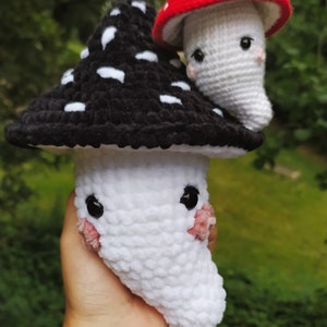 May include: Two crocheted mushroom plushies. One is black with white spots and the other is white with a red cap.