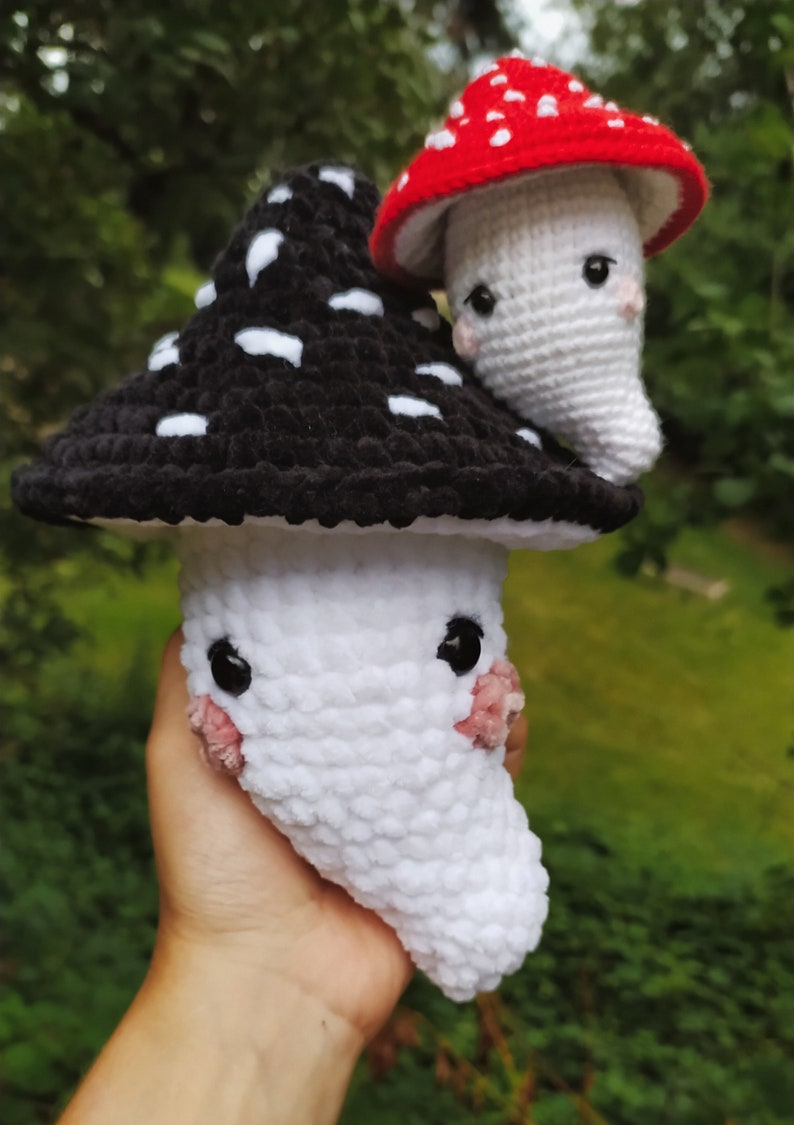 May include: Two crocheted mushroom plushies. One is black with white spots and the other is white with a red cap.