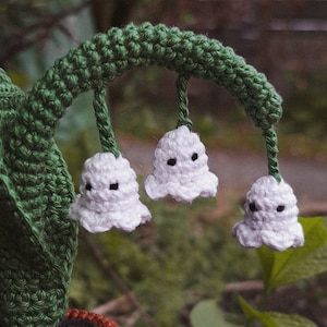 May include: A crocheted lily of the valley plant with white flowers and green leaves in a brown pot.
