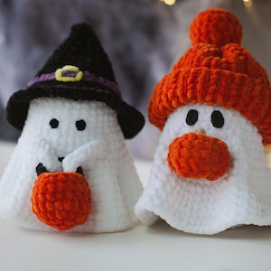 K&ouml;nnte beinhalten: Zwei geh&auml;kelte Geister-Ornamente, eines mit einem schwarzen Hexenhut und einem orangefarbenen K&uuml;rbis, das andere mit einer orangefarbenen Strickm&uuml;tze mit Bommel.