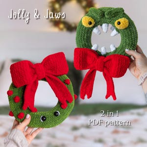 May include: Two green crochet wreaths with red bows. One wreath has a monster face with white teeth and yellow eyes. The other wreath has red pom-poms and black eyes. Text reads "Jolly & Jaws" and "2 in 1 PDF pattern".