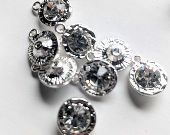 May include: A group of eight silver-toned metal charms with clear rhinestone accents. Each charm has a loop for attaching to a bracelet or necklace.