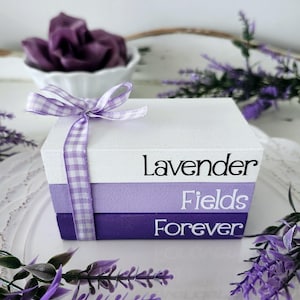 May include: A stack of three purple and white painted wooden boxes with a white gingham ribbon. The boxes are labeled "Lavender", "Fields", and "Forever".