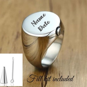 May include: A silver ring with a round top that can be opened to hold ashes. The top is engraved with the words "Name Date". A small fill kit is included.