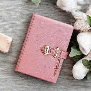 May include: A pink leather journal with a heart-shaped lock and key. The lock has the inscription "Class of 2023" and the key has the inscription "Tavia".