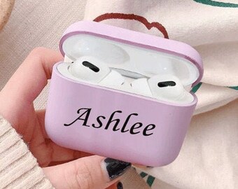 May include: A light purple case for wireless earbuds with the name "Ashlee" printed on the front.