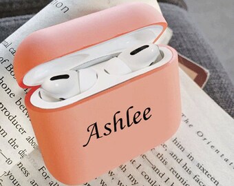 May include: A pink silicone case for wireless earbuds with the name "Ashlee" printed on the front.