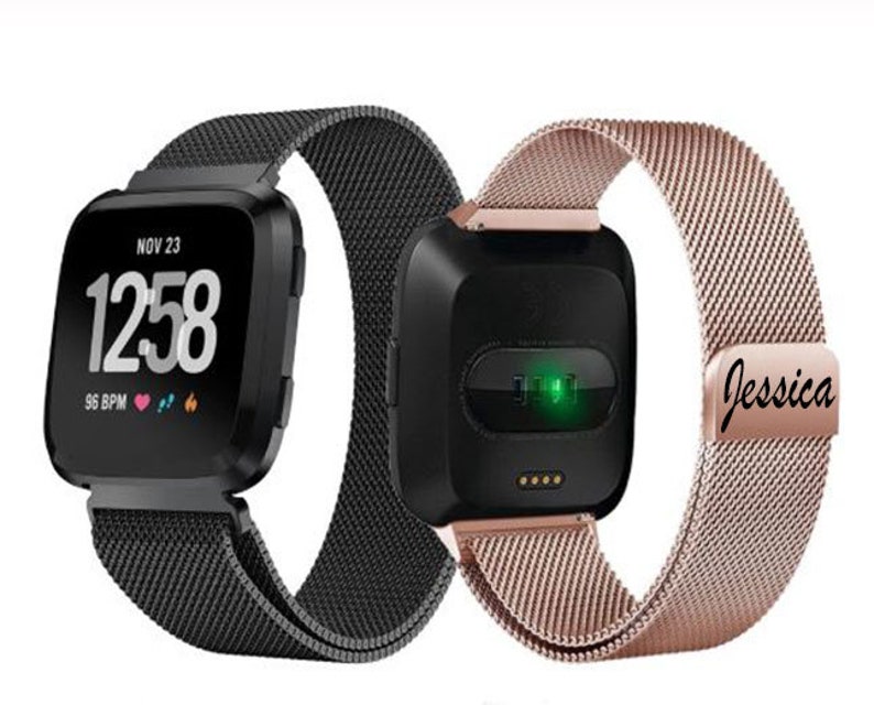 May include: Two smartwatches with black and rose gold mesh bands. One watch displays the time, date, and heart rate. The other watch has a green light and the name "Jessica" engraved on the band.