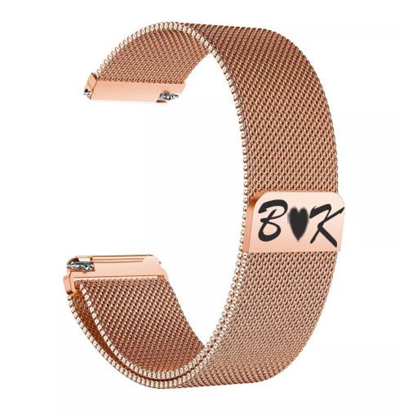 May include: Rose gold watch band with a mesh design. The band features a rectangular clasp with the letters "B&hearts;K" in black. The band is made of a woven metal material and has a shiny finish.