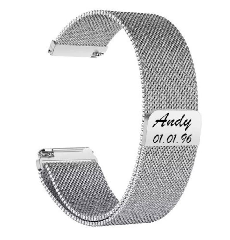 May include: A silver-colored watch band with a mesh design. The band has a rectangular plate with the name "Andy" and the date "01.01.96" engraved on it. The band is designed to attach to a watch.