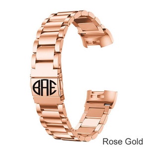 K&ouml;nnte beinhalten: Armband aus ros&eacute;goldfarbenem Metall mit einer monogrammierten Schlie&szlig;e, auf der "BAE" steht.