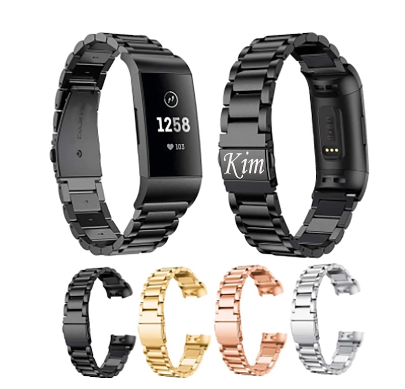 K&ouml;nnte beinhalten: Schwarze, goldene, ros&eacute;goldene und silberne Metall-Armb&auml;nder f&uuml;r einen Fitness-Tracker. Die Armb&auml;nder werden auf wei&szlig;em Hintergrund gezeigt. Das Armband links tr&auml;gt die Gravur "Kim".