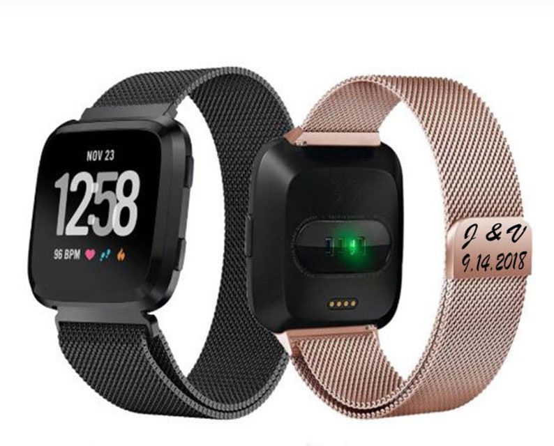 May include: Two smartwatches with black square faces and mesh bands. One watch displays the date, time, and heart rate. The other watch has a rose gold band with engraved initials and a date.