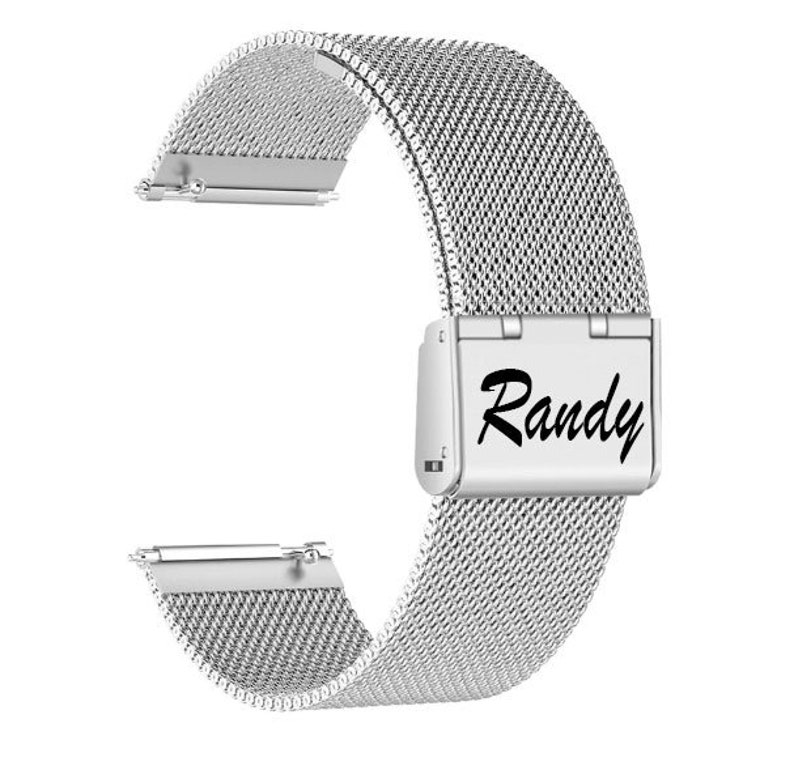 May include: A silver stainless steel watch band with a mesh design. The band features a rectangular clasp with the name "Randy" in black script. The band is designed to attach to a watch face.