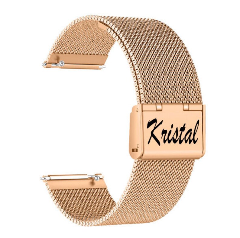 May include: Rose gold watch band with a mesh design. The band features a clasp with the word "Kristal" in a script font. The band is made of a fine, woven metal material and has a polished finish. The band is designed to attach to a watch.