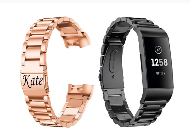K&ouml;nnte beinhalten: Zwei Metallarmb&auml;nder f&uuml;r eine Fitbit-Smartwatch. Ein Armband ist ros&eacute;goldfarben und tr&auml;gt die Gravur "Kate". Das andere Armband ist schwarz.