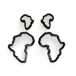 May include: Four black metal cookie cutters shaped like the continent of Africa. The cutters are in different sizes.