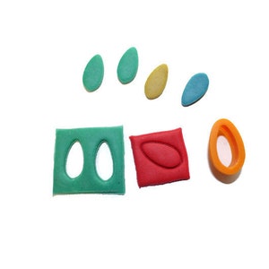 May include: A set of six colorful cookie cutters, including two green leaf shapes, a red oval, a yellow oval, a blue oval, and an orange oval. The cutters are made of plastic and are designed for making cookies.