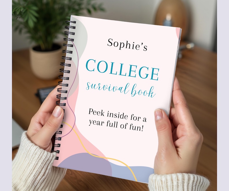 May include: A spiral-bound notebook titled "Sophie's COLLEGE survival book." The cover is light pink with teal and light blue text and abstract pastel shapes. The text "Peek inside for a year full of fun!" is also visible.