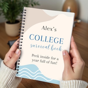May include: A spiral-bound notebook titled "Alex's COLLEGE survival book" with blue and beige accents. The cover includes the text "Peek inside for a year full of fun!" The notebook is held by a person wearing a cream-colored sweater.