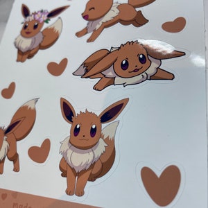 K&ouml;nnte beinhalten: Ein Blatt mit braunen und wei&szlig;en Aufklebern mit verschiedenen Illustrationen von Eevee, einem Pok&eacute;mon-Charakter. Die Aufkleber befinden sich auf einem wei&szlig;en Hintergrund mit braunem Rand und dem Text "made with love".