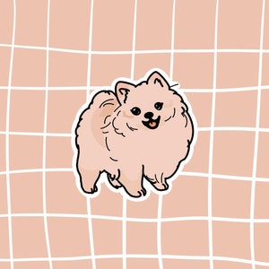 May include: A sticker featuring a cartoon Pomeranian dog in a standing pose. The dog is light tan with a fluffy coat, black eyes, and a smiling expression. The background is a grid pattern in a light brown color.