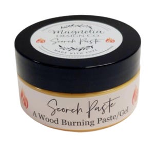 May include: A small, round jar of "Scorch Paste" wood burning gel. The jar has a black lid and a cream-colored label with the product name and "Magnolia Design Co." printed on it. The label also features flame graphics.