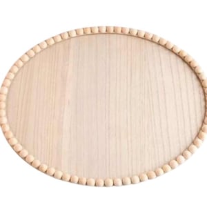 May include: A round wooden tray with a beaded edge. The tray is light brown and has a smooth surface.