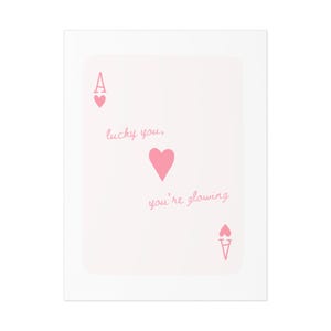 May include: A pink playing card with the Ace of Hearts. The card has the text "lucky you, you're glowing" written on it.
