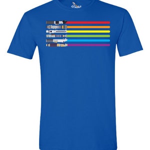 K&ouml;nnte beinhalten: Ein k&ouml;nigsblaues T-Shirt mit einem Regenbogenstreifen-Design, das mehrere Lichtschwerter zeigt. Die Lichtschwerter sind in einer horizontalen Linie angeordnet, wobei die Griffe nach links zeigen.