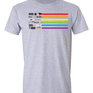 K&ouml;nnte beinhalten: Ein graues T-Shirt mit einem Regenbogenmuster aus Lichtschwertern. Die Lichtschwerter sind horizontal angeordnet, wobei das rote Lichtschwert oben und das violette Lichtschwert unten ist.