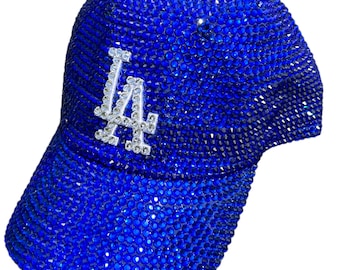 May include: A blue baseball cap with a white "LA" logo, completely covered in blue rhinestones.