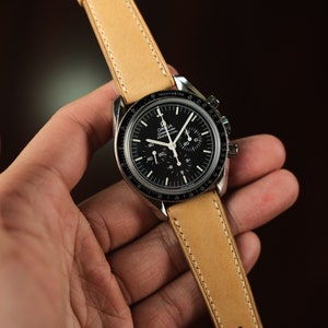 May include: A black chronograph wristwatch with a brown leather band. The watch face has white markings and a date window.