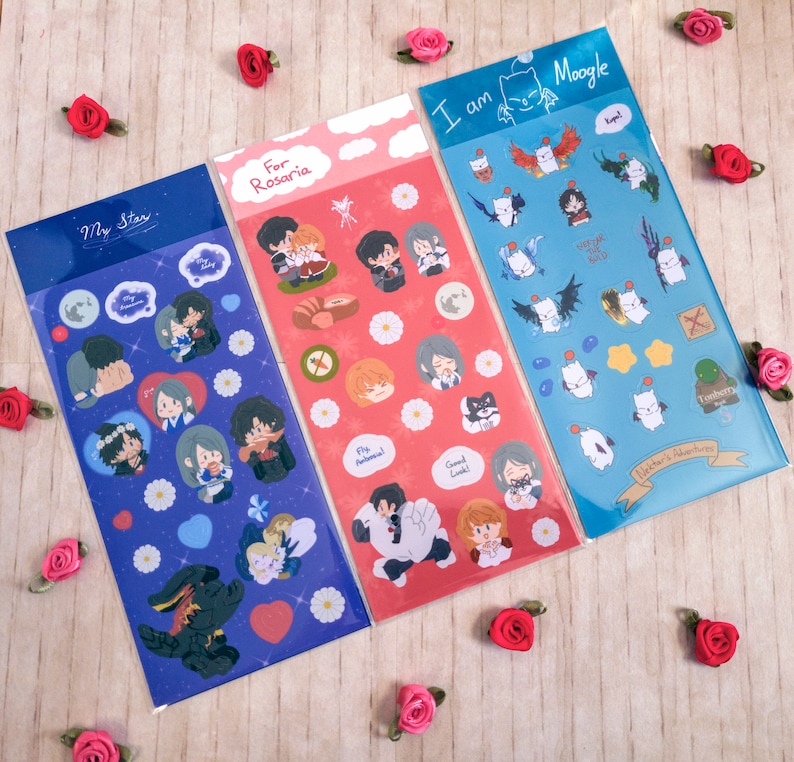 Pu&ograve; includere: Tre fogli di adesivi con illustrazioni di cartoni animati e testo. I fogli sono blu, rosa e azzurro. Il foglio blu dice "My Star" e presenta coppie e un coniglietto nero. Il foglio rosa dice "For Rosaria" e ha coppie e fiori. Il foglio azzurro dice "I am Moogle" e ha personaggi dei cartoni animati.