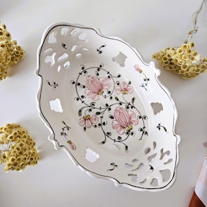 Puede incluir: Plato de servir ovalado de cerámica blanca con un diseño recortado y un patrón floral en rosa, verde y amarillo.
