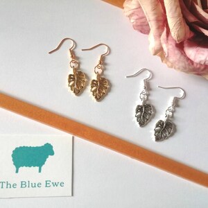 May include: Two pairs of earrings with leaf-shaped charms. One pair is gold and the other is silver.