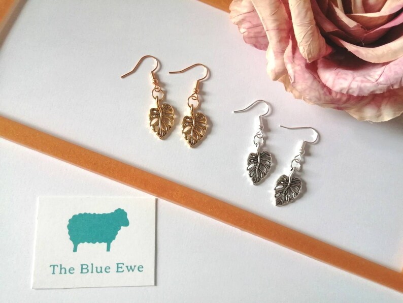 May include: Two pairs of earrings with leaf-shaped charms. One pair is gold and the other is silver.